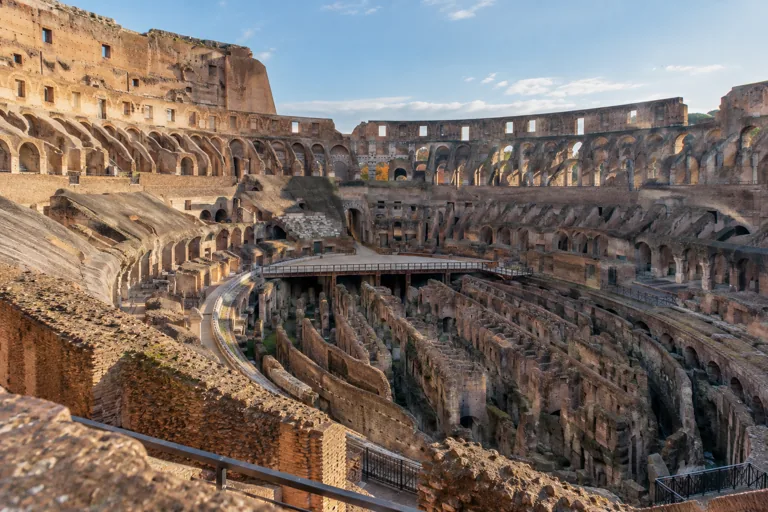 Exposed brick corridors below the Colosseum arena, seen from an upper walkway; AI-generated editorial illustration.